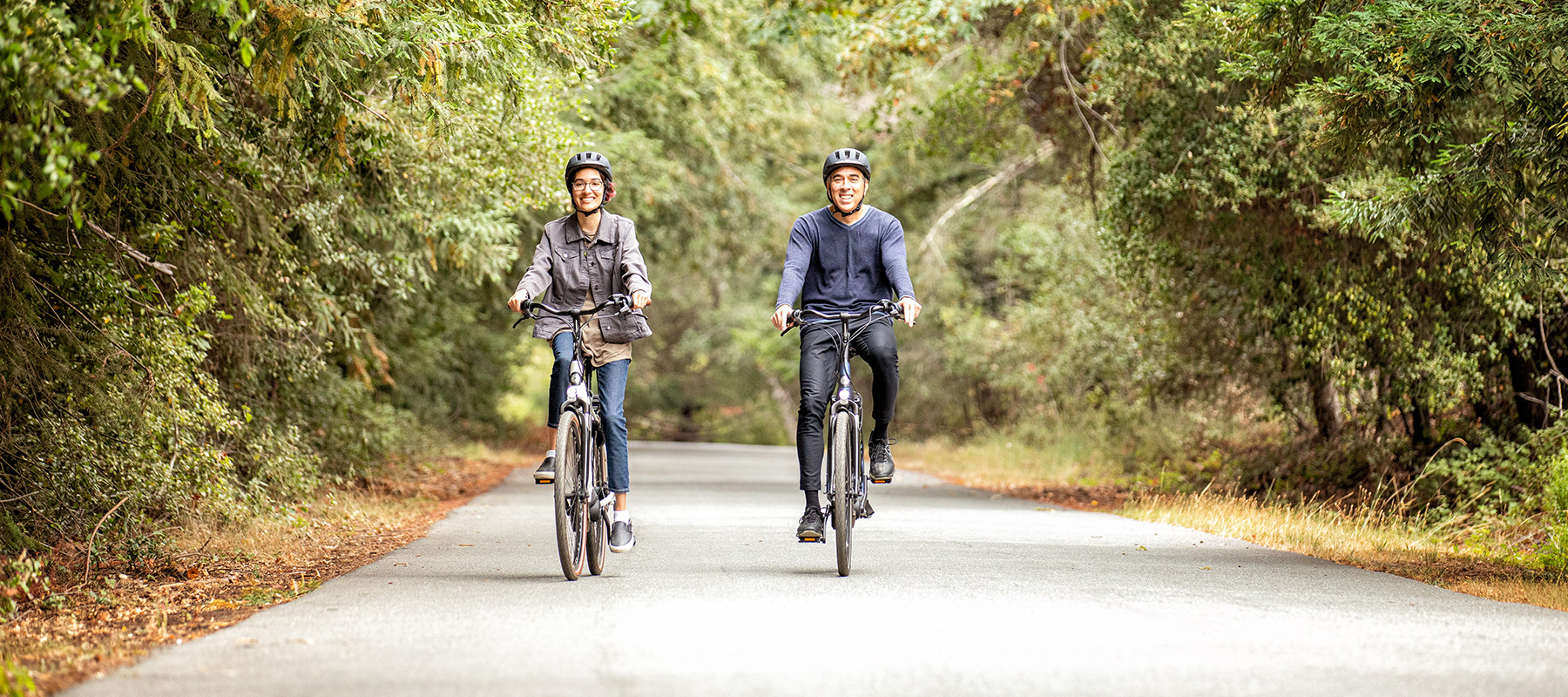 mand og kvinde med hjelm på elcykel.